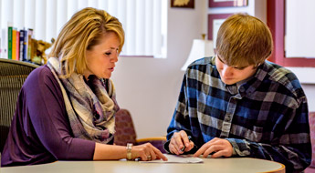 !Image shows a financial aid employee helping a student complete the paperwork needed to apply for financial assistance.