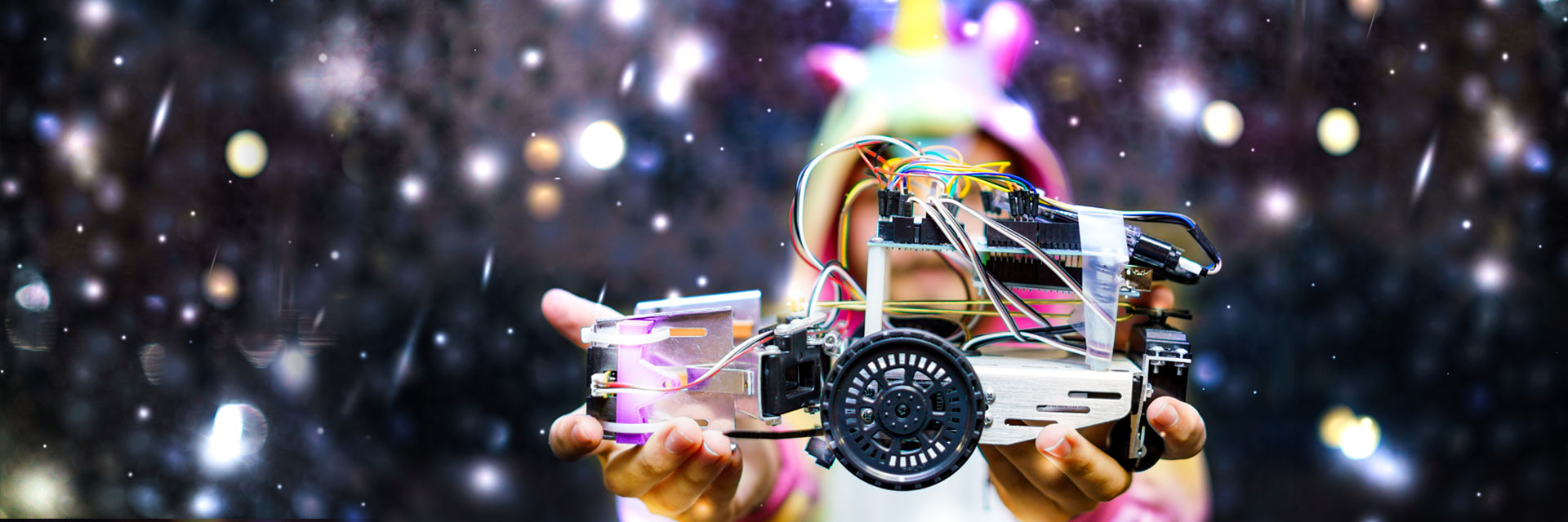 Small robot held in the hands of a student dressed as a unicorn