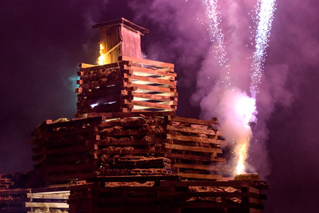 Hundreds of wooden railroad ties stacked into a tall tower on the lawn of the bonfire field. The ties will later be set on fire for the annual bonfire celebration.