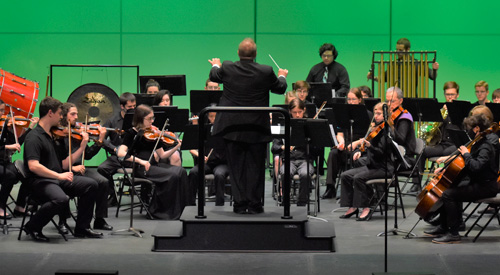 !Students performing on musical instruments on stage