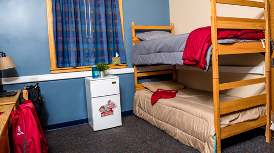 Bunk beds and a mini fridge in a typical room in Percopo Hall.