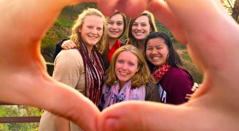 Members of the Panhellenic Council smiling and framed by two hands making a heart shape.