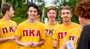 Several fraternity brothers smiling and wearing their fraternity T-shirts