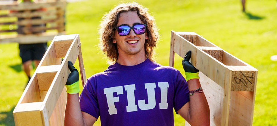 A member of Fiji helps build the Homecoming bonfire.