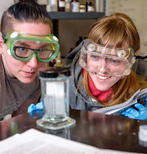 Two female students wearing lab goggles