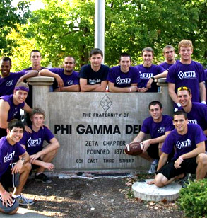 Members of the FIJI fraternity pose next to their house sign wearing their purple colors. 