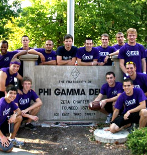 Members of the FIJI fraternity pose next to their house sign wearing their purple colors.