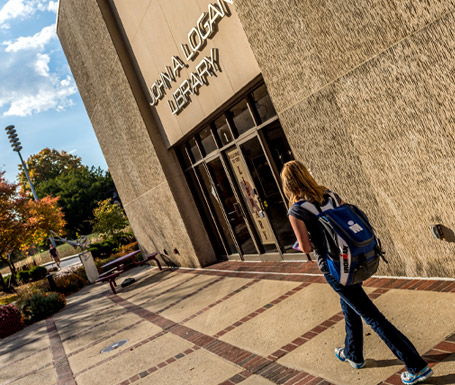 !Female student walking in front of the John A. Logan Library.