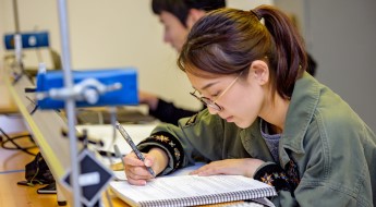 !Female student writing in a notebook.