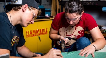 !Two students working on an electrical computer project.