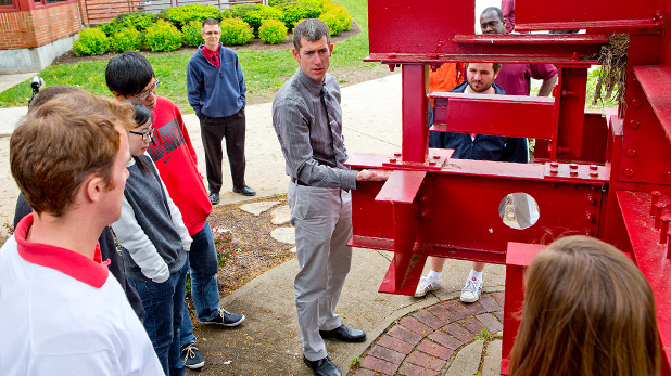 Students and professors examine beams in outdoor lab