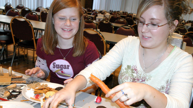 Students creating a car using crackers, pretzel sticks and other ingredients.