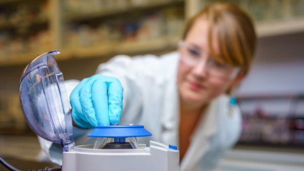 Female student placing test sample into lab machine