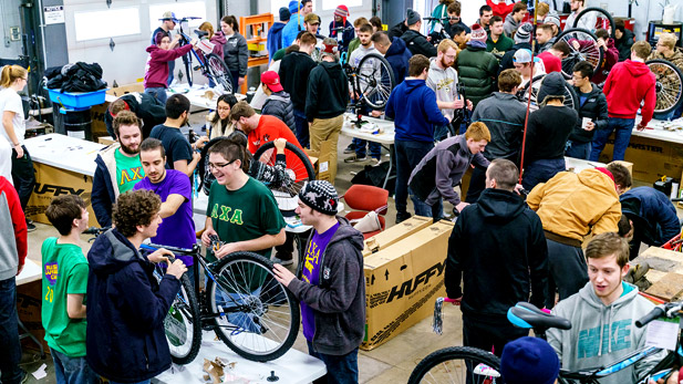 Two smiling female students assembling a bicycle