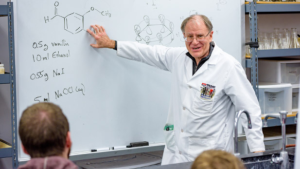 Bruce Allison gesturing to chemical formulas on a white board