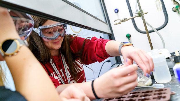 Female students wearing science lab gear working on a project