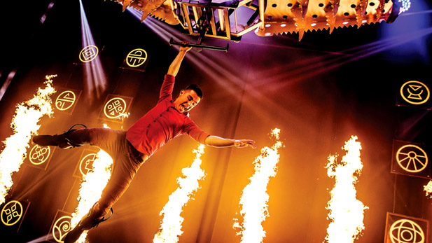 Magician performing fiery aerial trick.