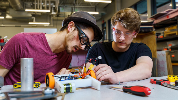 Two students working on a small combat robot