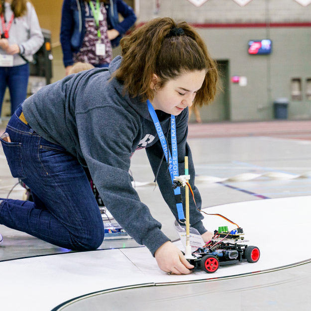 Student competitors watch as autonomous vehicles navigate a track