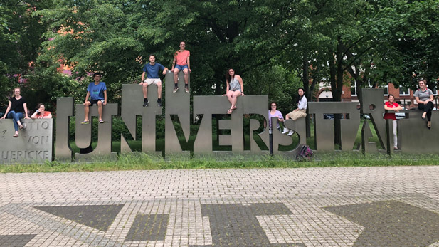 Students sitting on a sign at a German University