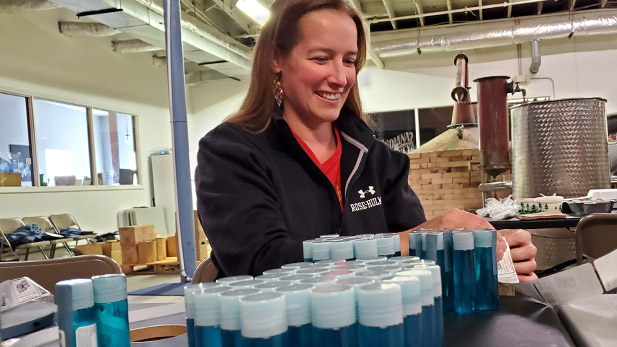 Alumna Stefani Vande Lune fills bottles with hand sanitizer at the Indiana Whiskey Co.