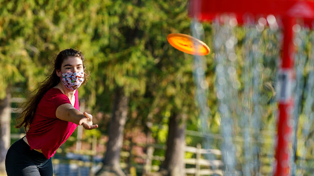 Student throwing a disc at a basket on Rose-Hulman's new nine-hole disc golf course.