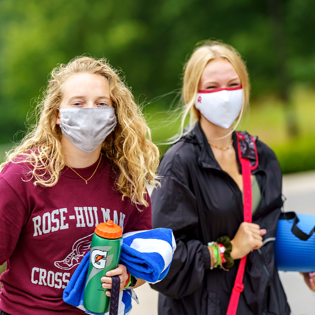 Students wearing COVID-19 prevention masks walking on campus.