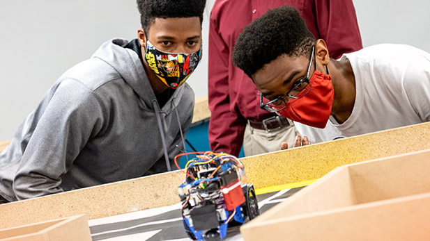 Students watch as their robot searches for chickens and zombies.