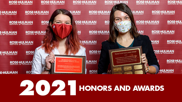 Two female students wearing masks holding their award plaques.