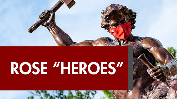 Image shows sculpture of the self-made-man wearing a COVID-19 mask above the words Rose Heroes.