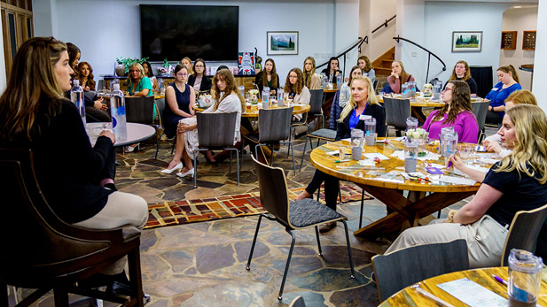 A group of women alumni and students gather in a room at the Rose-Hulman campus.