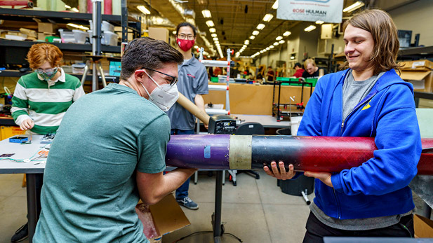 Members of Rose-Hulman's Rocketry club carry a rocket.