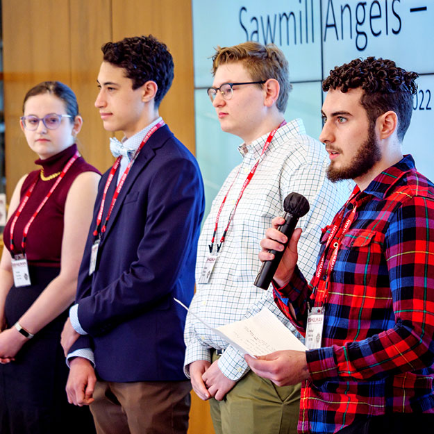 A group of individuals stand before the crowd at the Sawmill Society weekend event at Rose-Hulman.