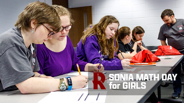 A group of students sit at a table working on math problems.