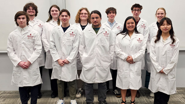 Eleven chemistry and biochemistry students proudly wear their new white lab coats, embroidered in red on the left chest with the Rose-Hulman logo and the student's name.