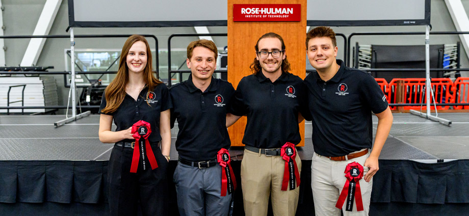 Four students hold red award ribbons.