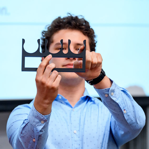Two students present their project, which includes a large cylinder on wheels, at Engineerathon.