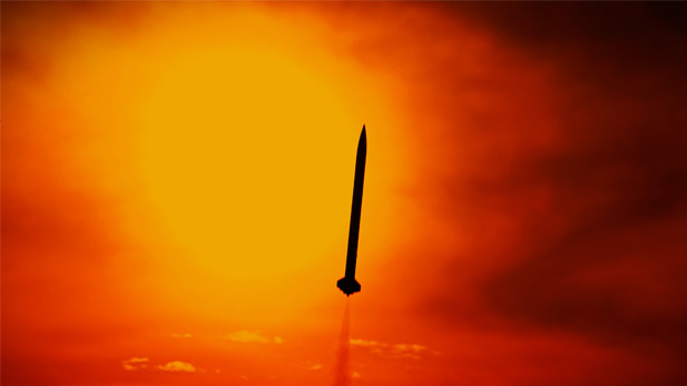 A rocket flying in silhouette in front of a sunset.