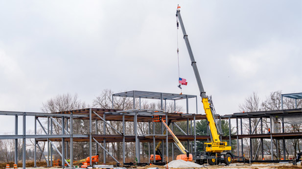 A crane lowers a beam to the highest point of the Innovation Grove structure.