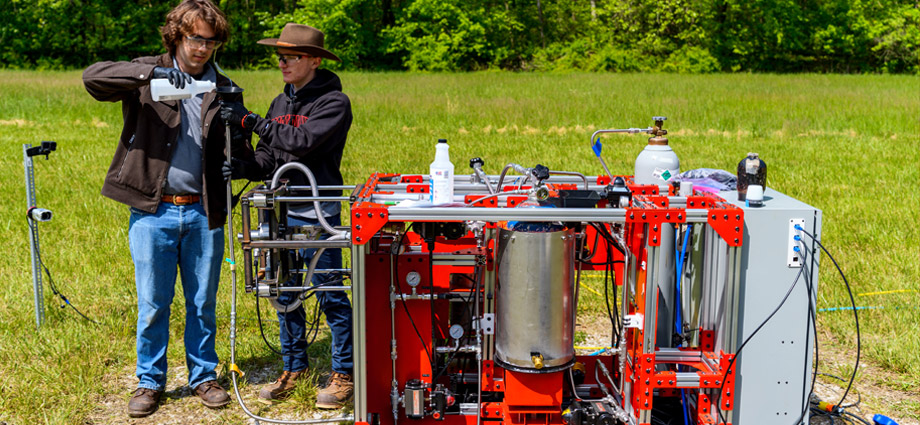 Two students pour propellant into the hot fire engine.