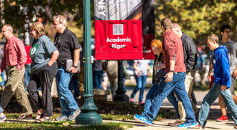 Students and parents walk across campus on a sunny day during a campus visit program.