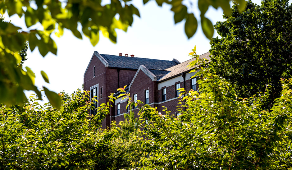 : The top floor of a Rose-Hulman dormitory with green leaves in the foreground.