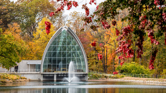 Exterior view of White Chapel with Speed Lake in foreground and fall foliage.