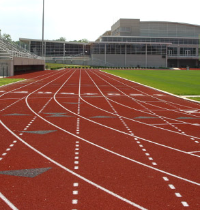Image shows all eight lanes of the William Welch track around the Phil Brown football field at Rose-Hulman. The Sports and Recreation Center is in the background.